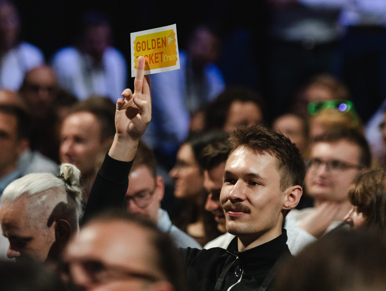 man won the golden ticket at the opening and is showing it by holding it in the air in the audience