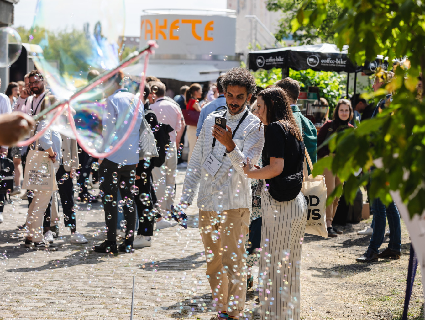 festival area outside, people standing, talking and you can see air bubbles 