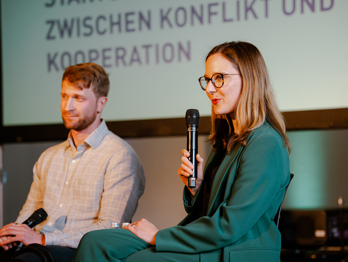 woman and man sitting on a stage holding a presentation