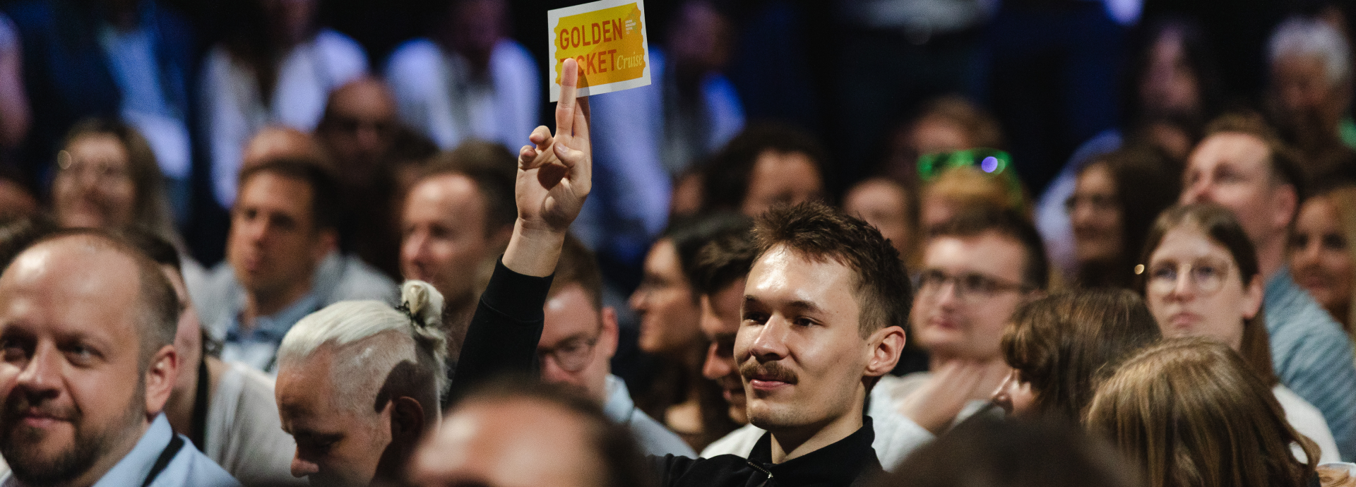man won the golden ticket at the opening and is showing it by holding it in the air in the audience