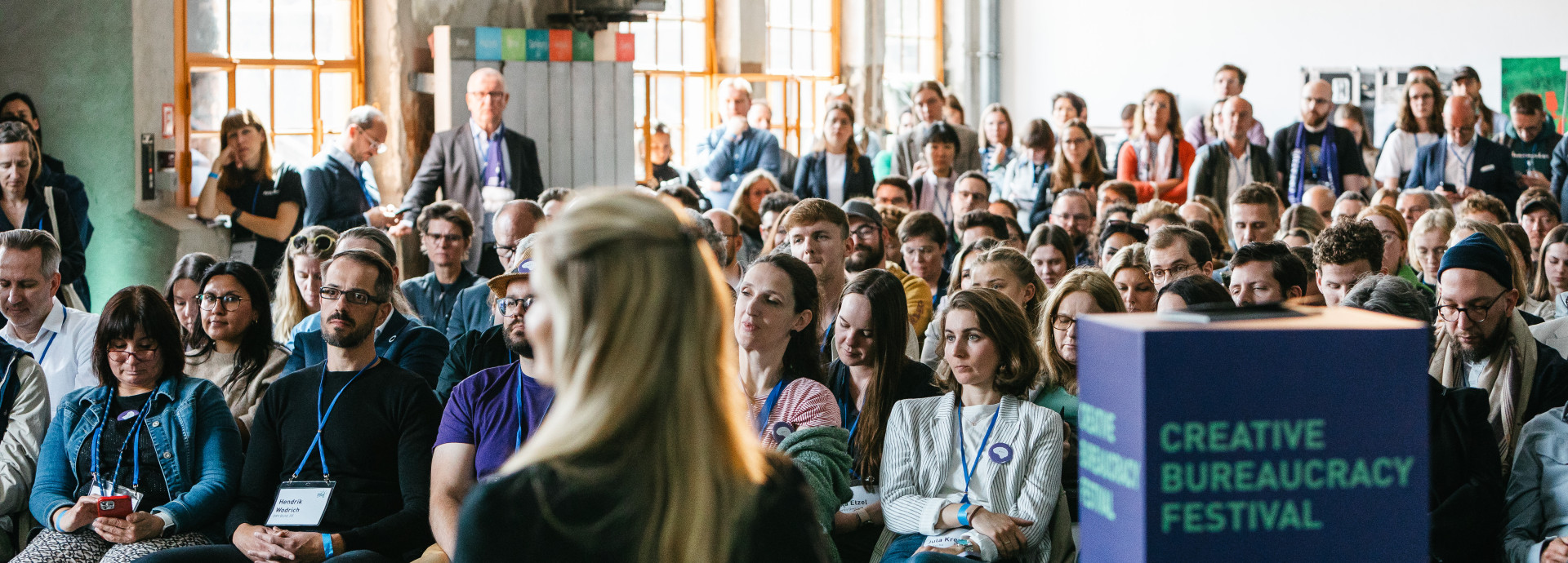 a woman as a speaker talking infront of a big crowd 