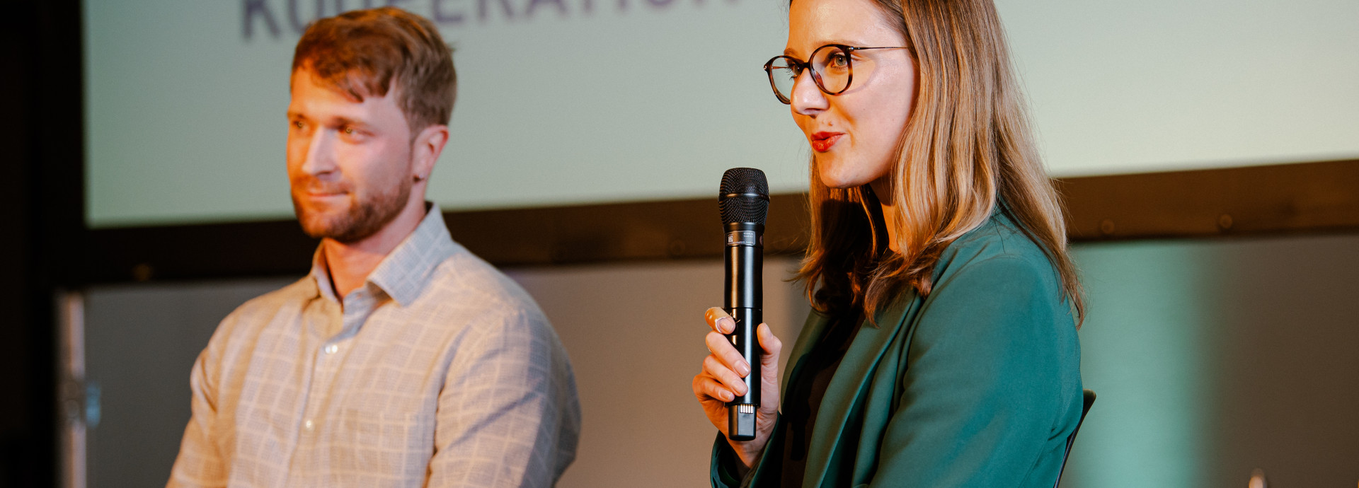 woman and man sitting on a stage holding a presentation