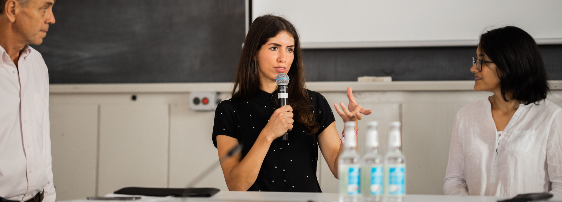 female speaker talking and two other people listening 