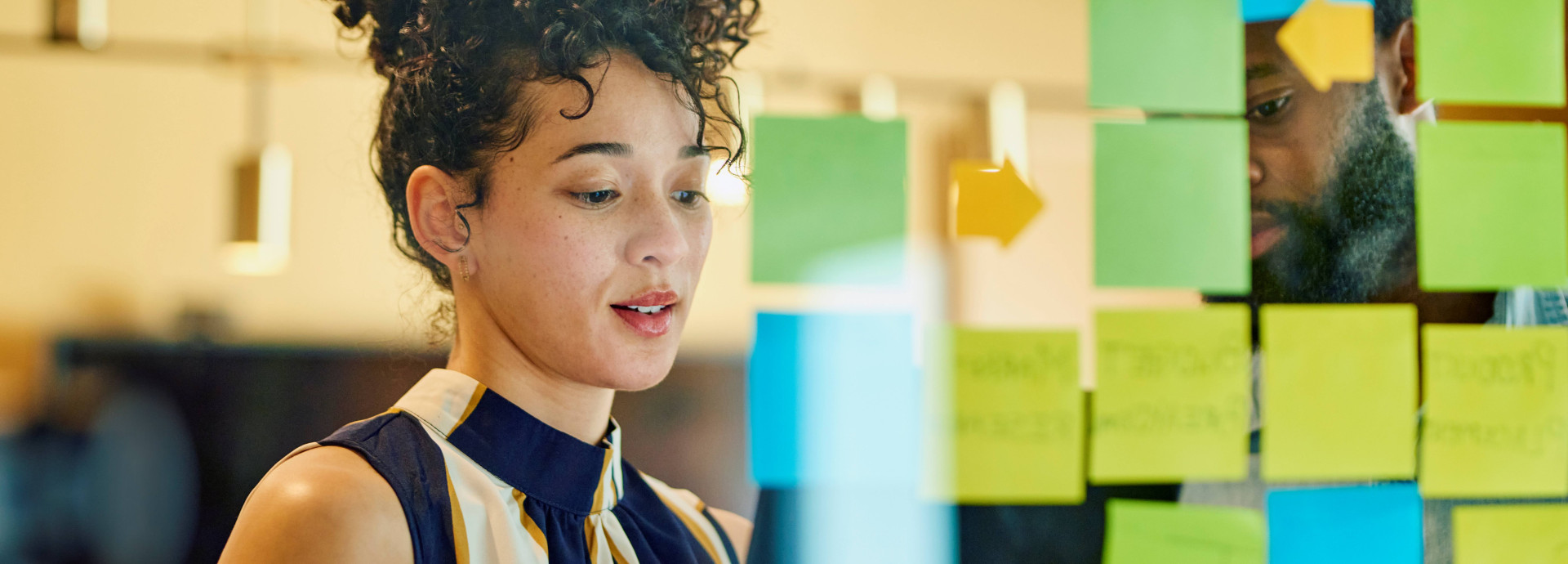 Individual standing in front of glass with sticky notes on it