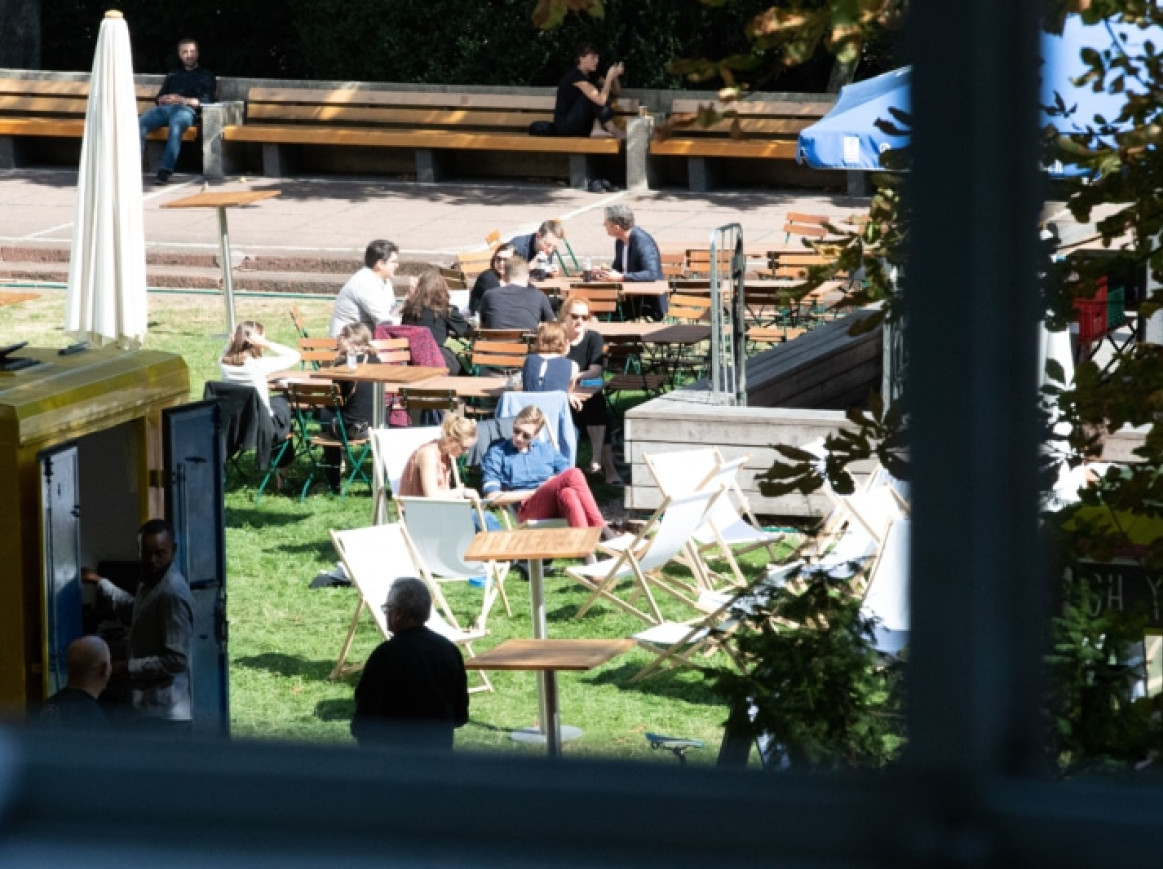 Außenbereich des Festivals, Stühle auf dem Gras und Menschen, die sitzen und sich unterhalten