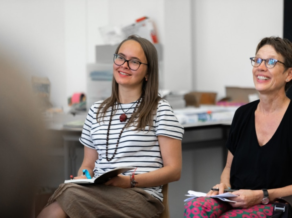 two woman sitting and smiling 