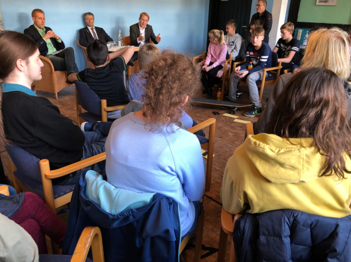kids listening to adults , sitting on chairs in a circle 