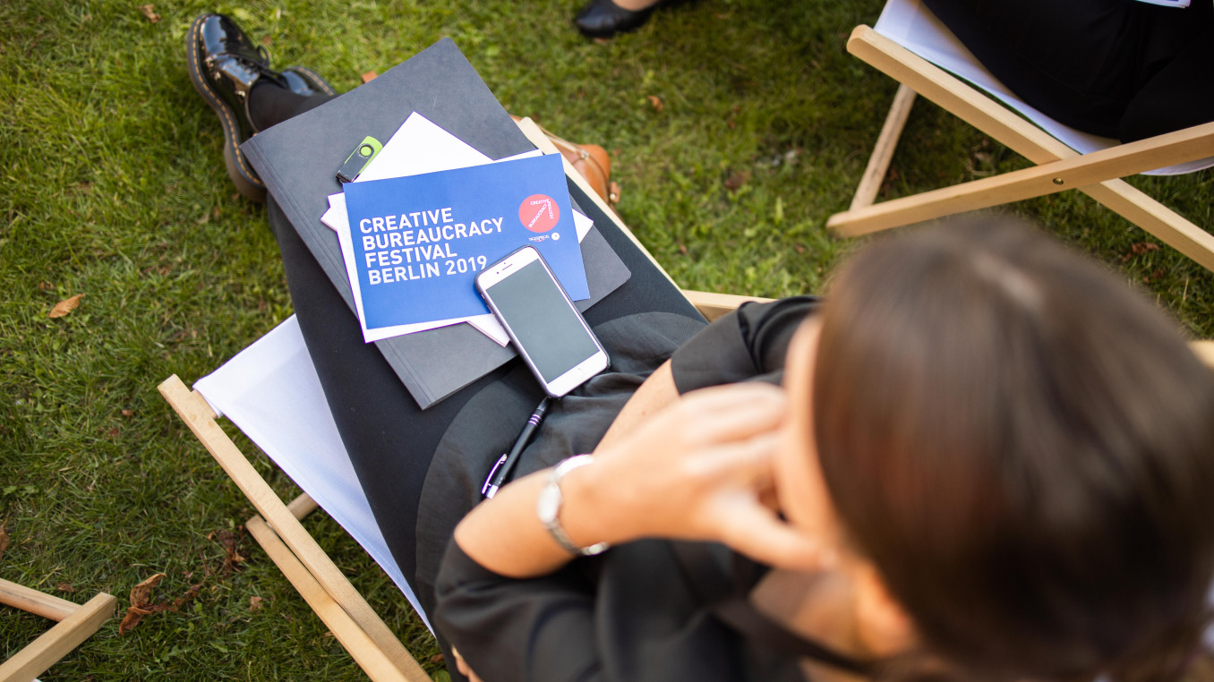 woman sitting outside with a festival 2019 card, papers and phone on her lap