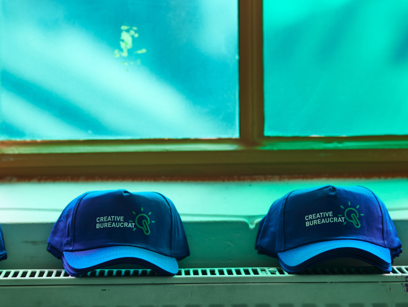 Creative Bureaucracy Festival-Merch (4 Caps) auf einem Heizkörper