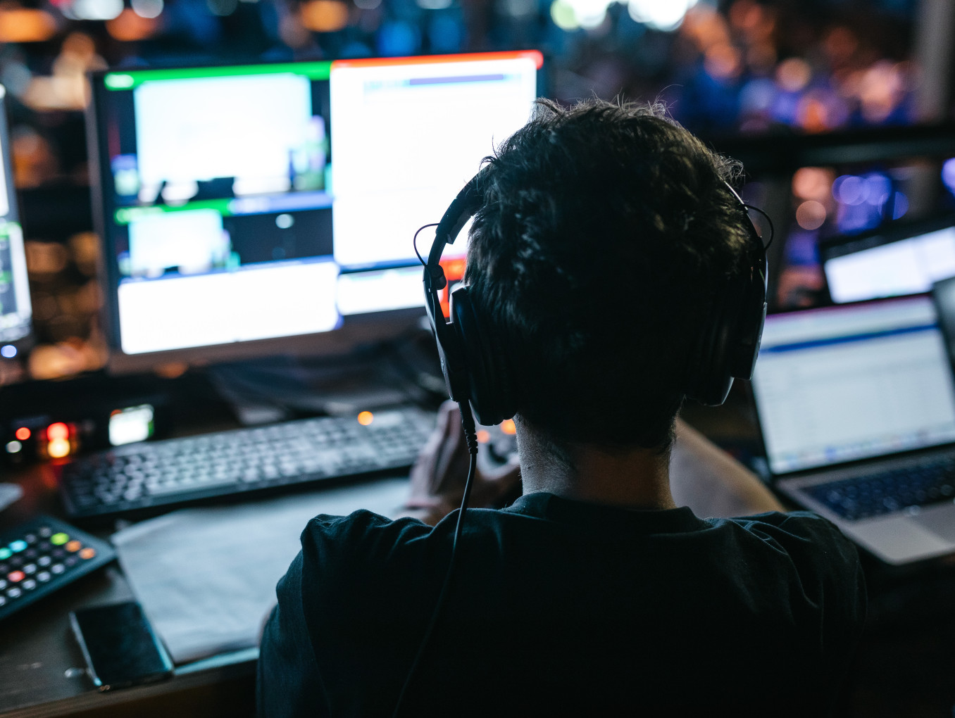 man with headphones sitting on a laptop