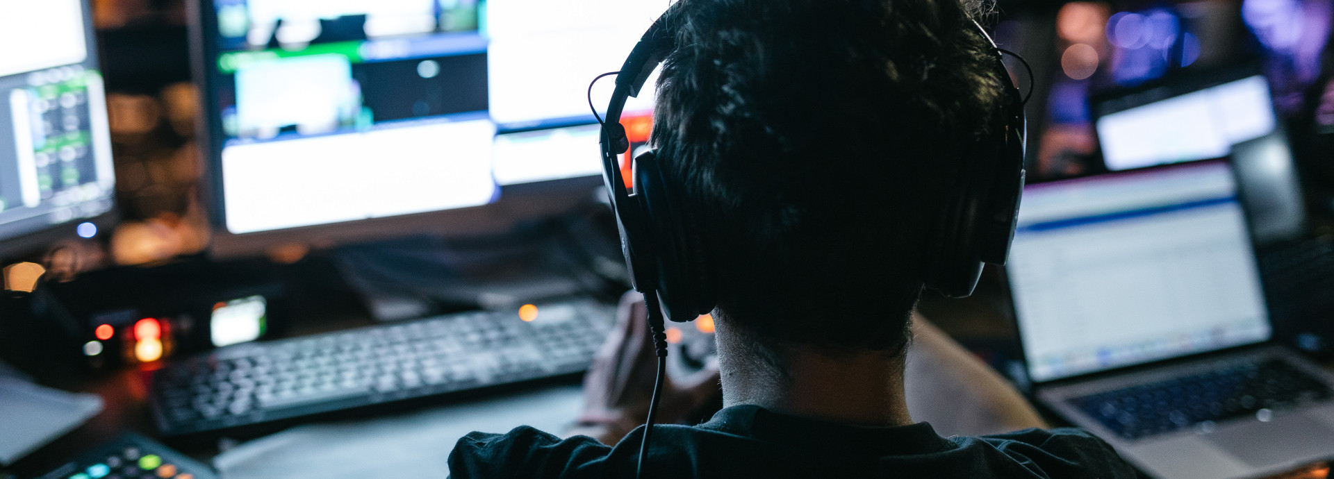 man with headphones sitting on a laptop