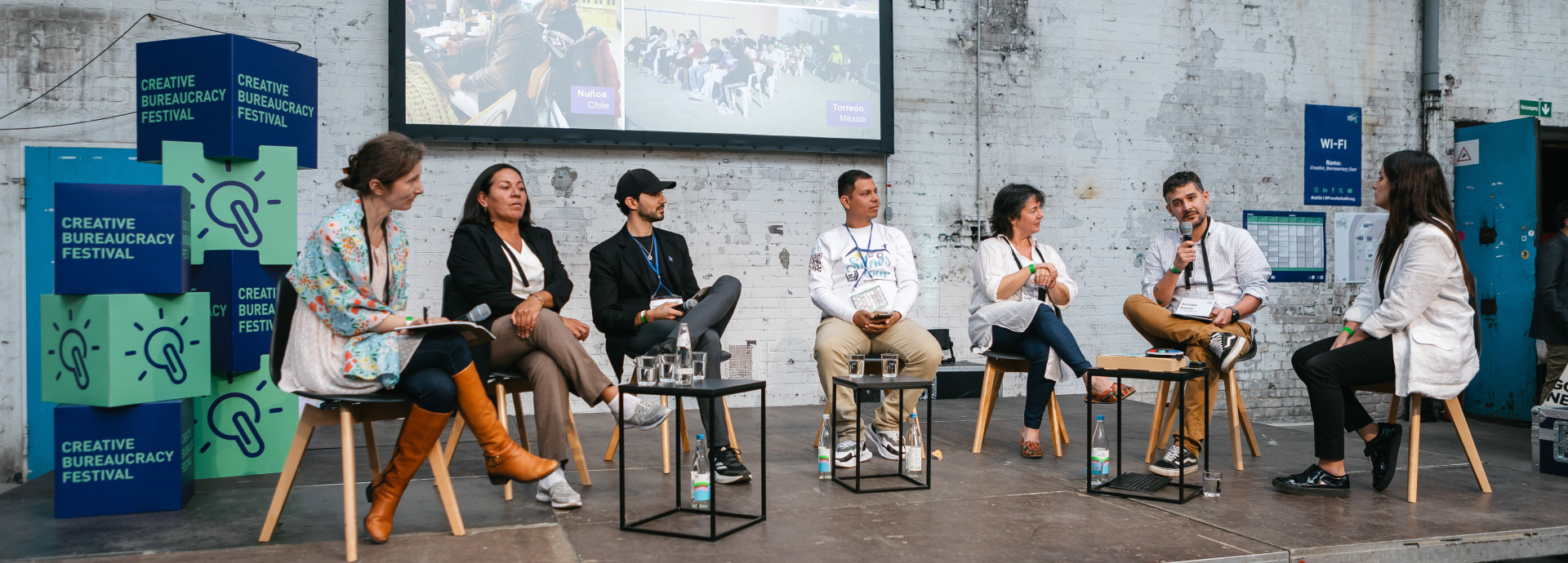 seven speaker sitting on stage and having a discussion