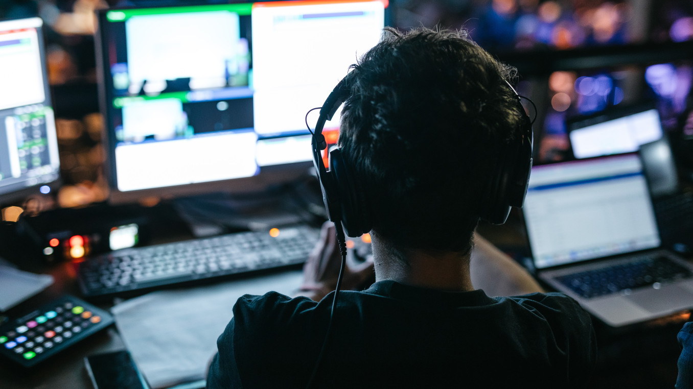 man with headphones sitting on a laptop 